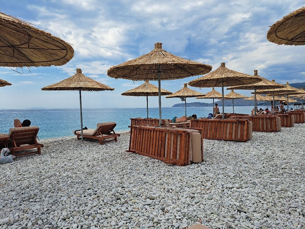 borsh beach albania con playas de piedras , agua turquesa y tumbonas