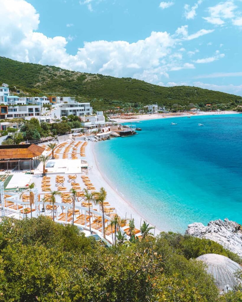 himare beach con aguas turquesa , tumbonas y playa para turistas